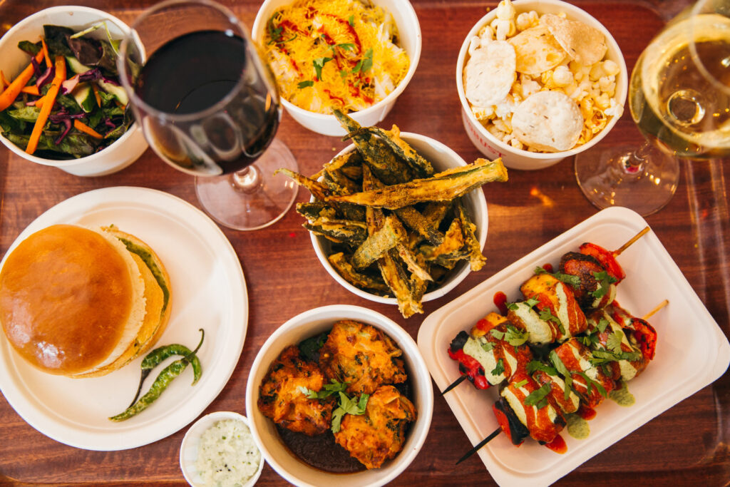 A selection of dishes, a glass of red wine and a glass of white wine at Bundobust