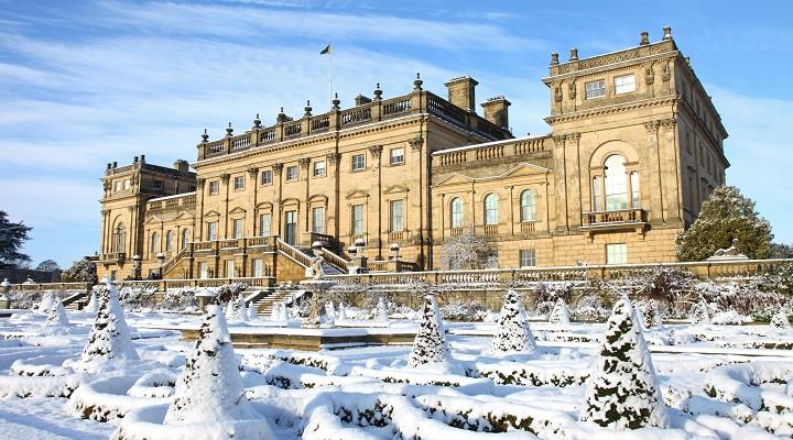Exterior of Harewood House, with the front terrace covered in snow, the sky is blue and the sun is bright