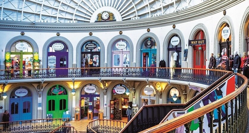 An interior view of the iconic Leeds Corn Exchange - a domed roof and colourful shop front entrances.