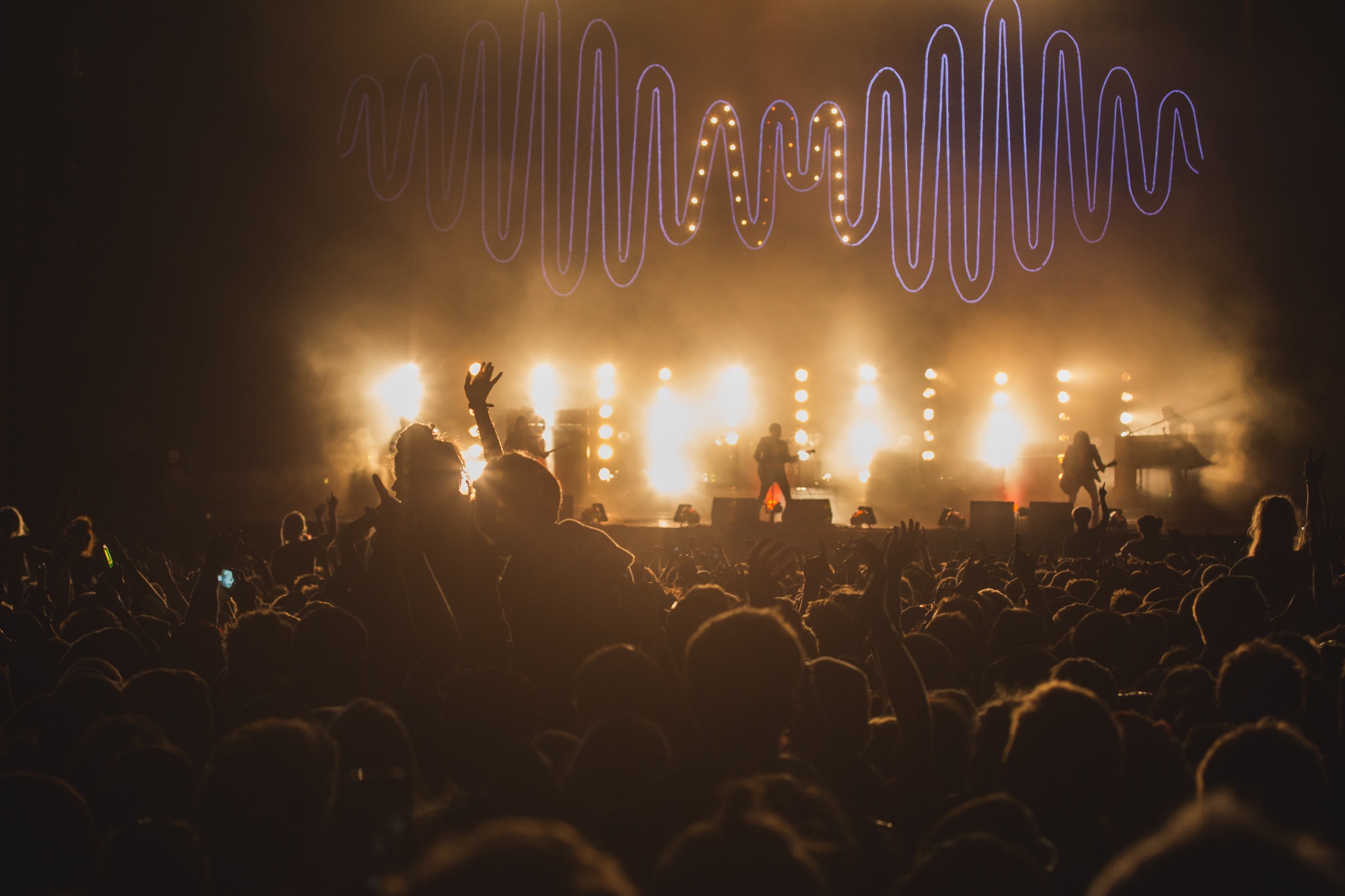 Picture of a crowd inside a concert hall watching a music gig with stage lights on and musicians on the stage during Leeds Festival