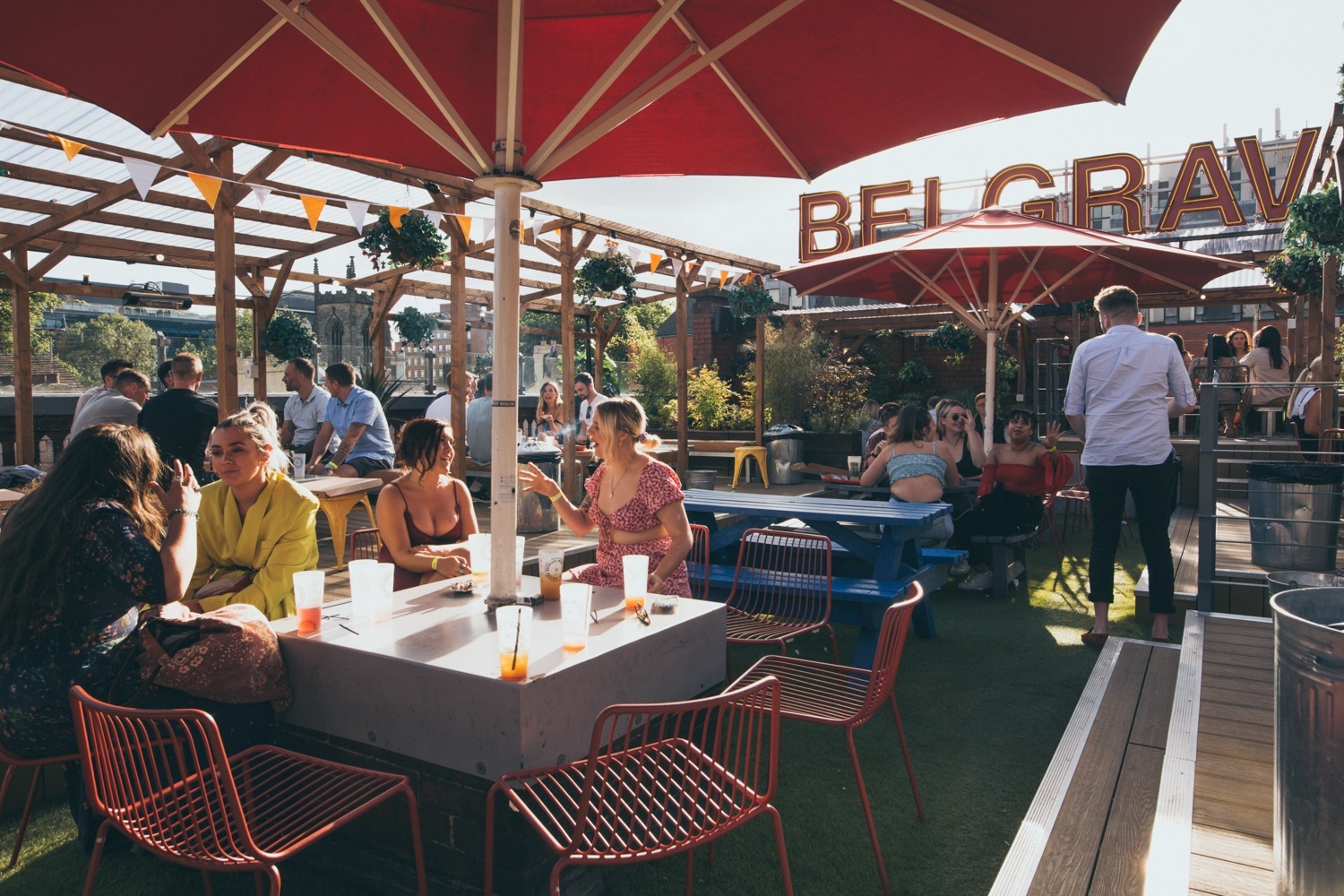 people sat at a table under a large parasol having drinks