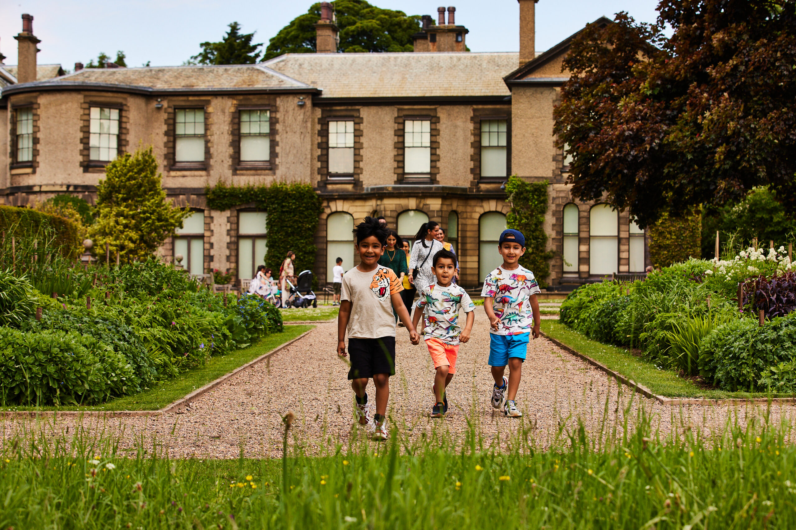 Lotherton Hall exterior, with children playing on front lawn. Sun is shining.