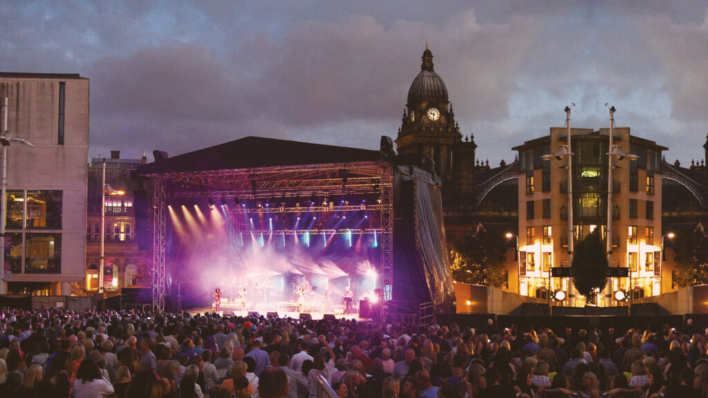 Stage at Millennium Square lit up with performance in front of crowd in Leeds
