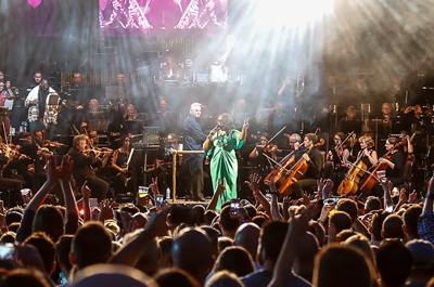 Performance with singer and full orchestra on stage with crowds cheering at Millennium Sqaure