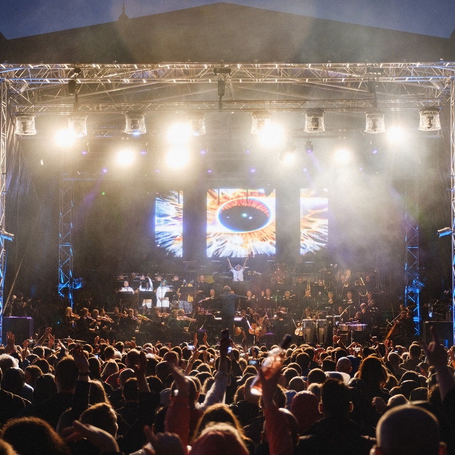 Photo of the crown enjoying concert outside with singer on a stage in the background