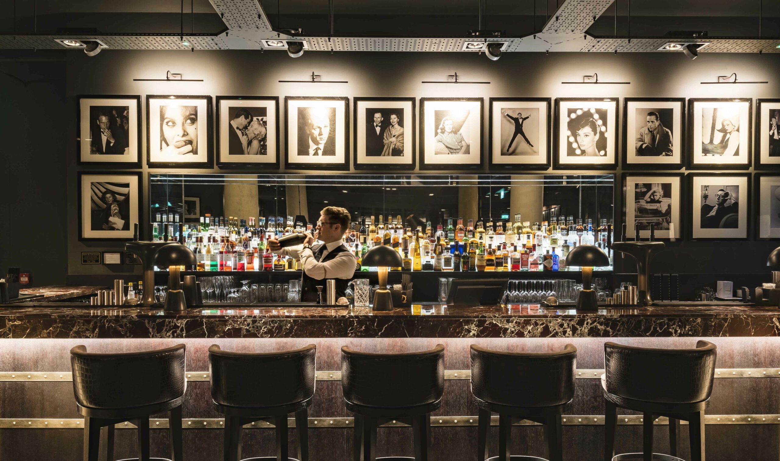 A bartender creating a cocktail at a black and white themed bar.