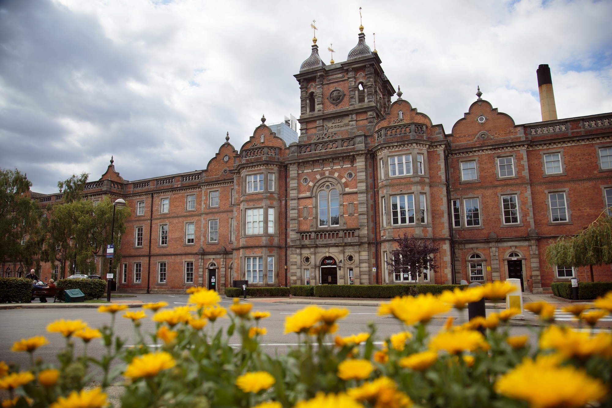 Exterior view of Thackray Museum of Medicine, a Grade II listed building in Gothic Victorian style. Yellow flowers in the foreground.