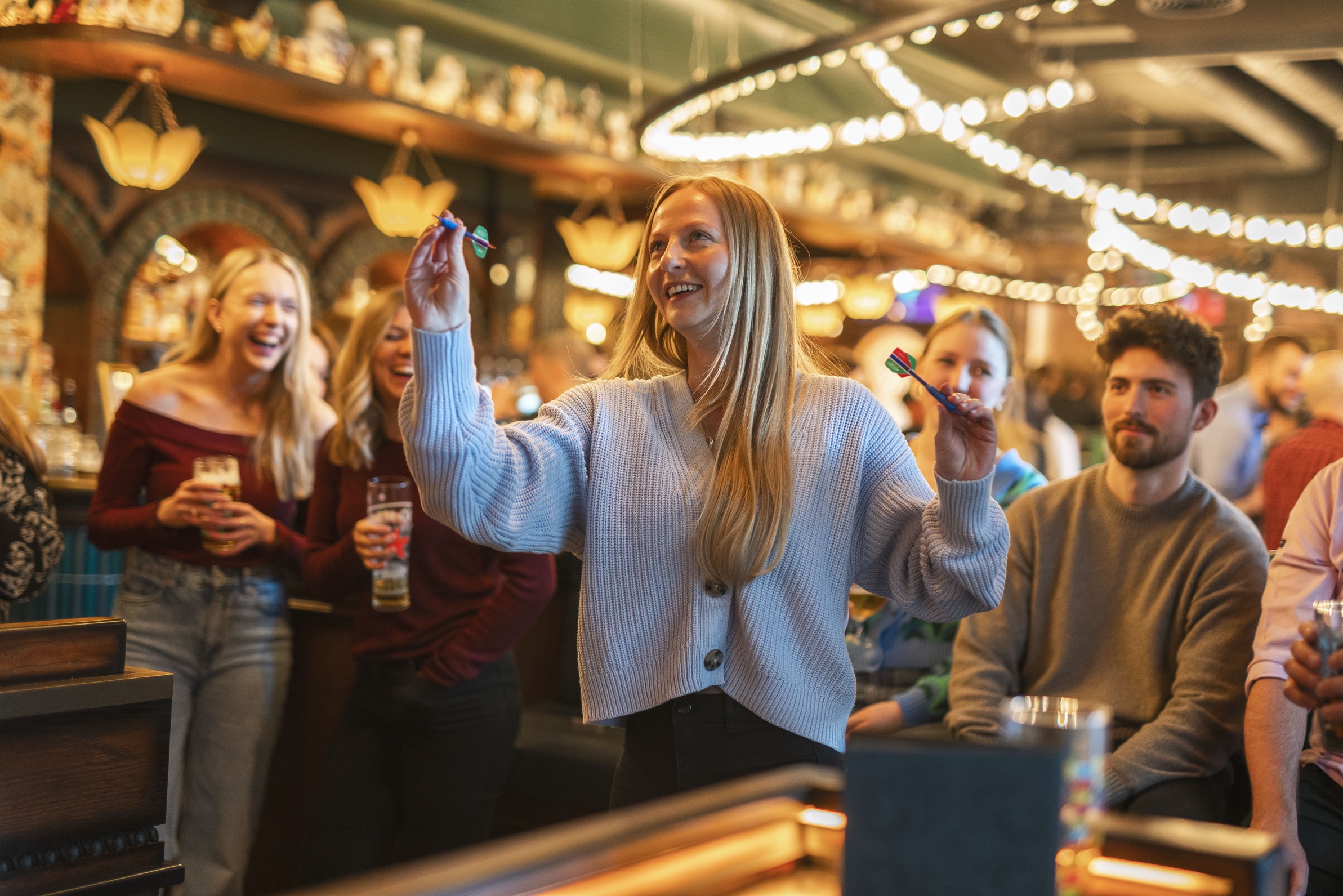 Lady with a group of friends playing darts at Flight Club
