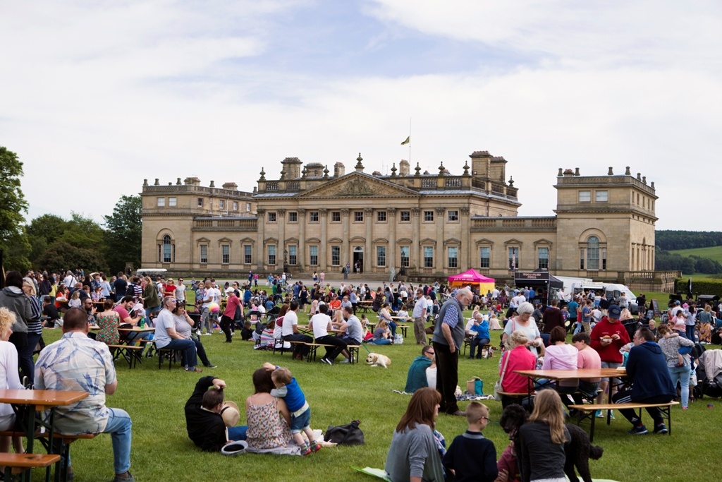 A crowd of people on the grass in front of Harewood House