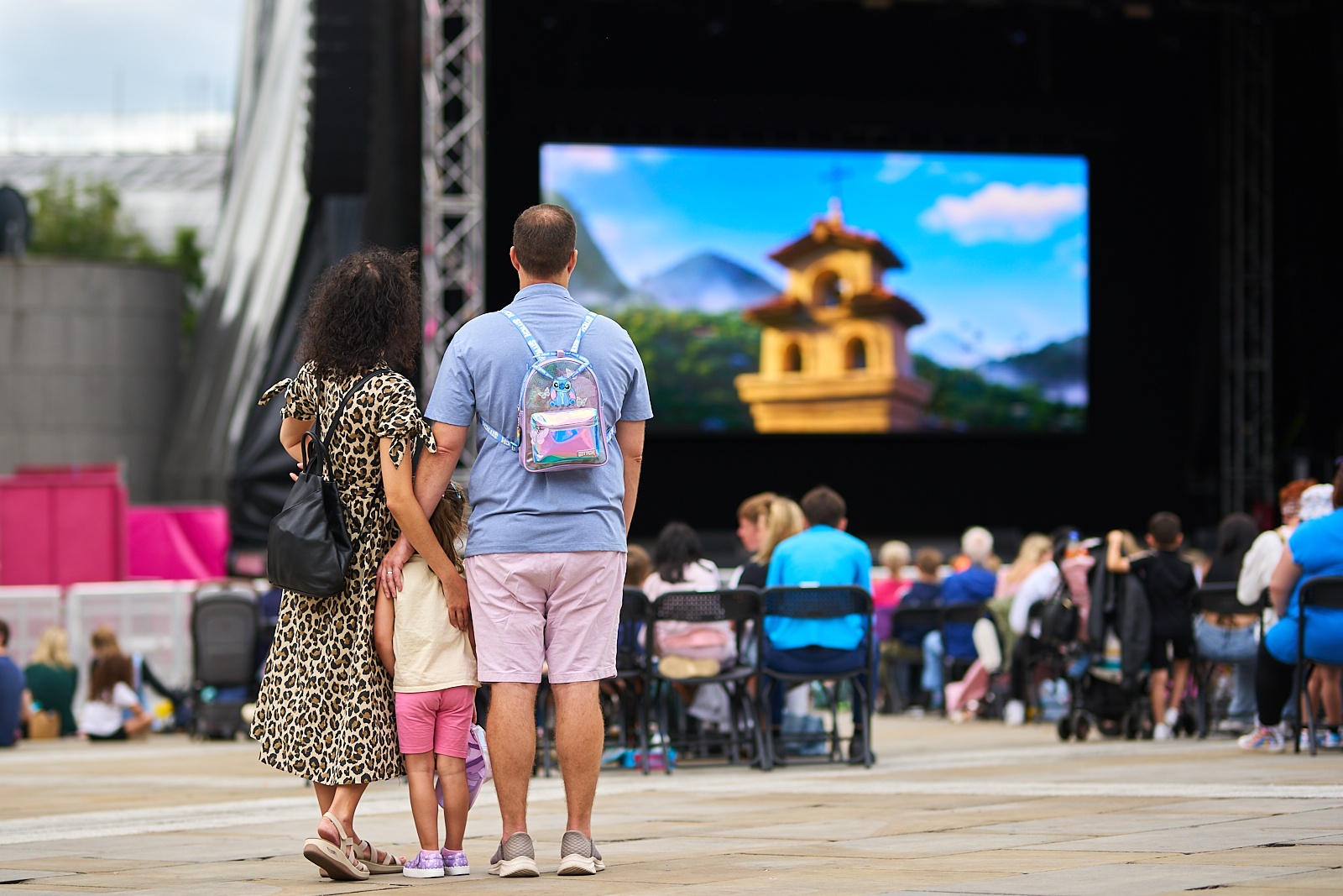 a family watching a big cinema screen in an outdoor square