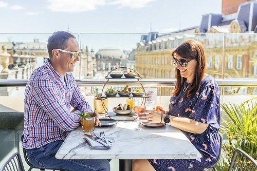 A couple enjoying afternoon tea on a terrace overlooking Leeds city centre