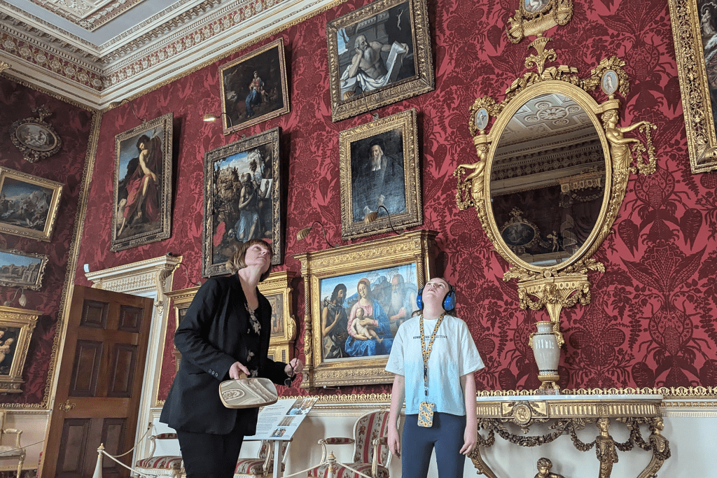 A young girl wearing headphones enjoys an interior portrait gallery at Harewood House.