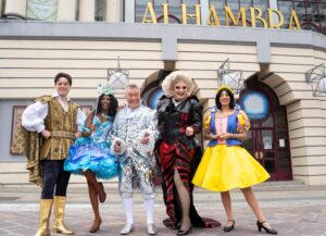 a group of actors outside the theatre in pantomime colourful clothes