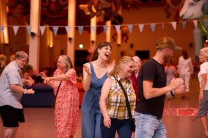 a group of people dancing inside with colourful bunting around them