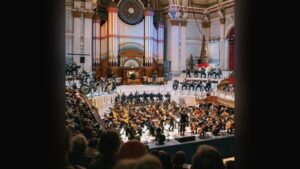 an orchestra playing in an ornate building with a large organ behind them