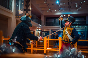 someone dressed as a rat king and someone dressed in traditional army uniform as a nutcracker fighting with swords