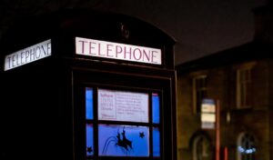 an old telephone box at night time lit up