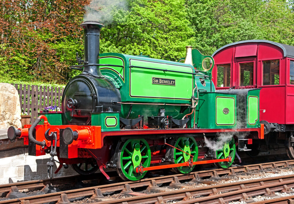 a bright green and red old steam train running on a track