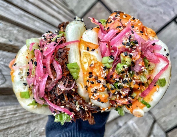 a hand holding a colourful bao dish