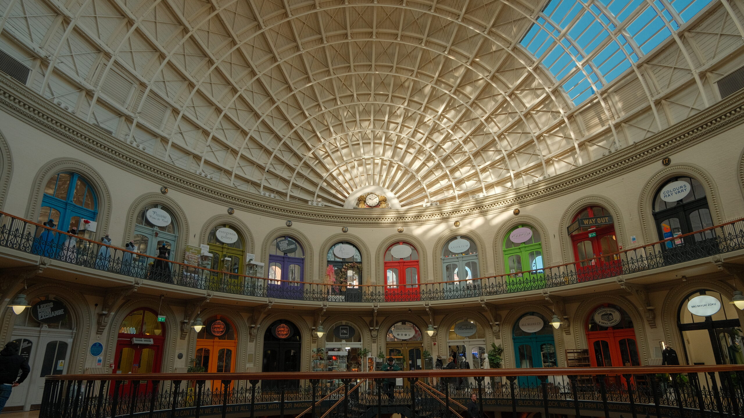 An interior view of the iconic Leeds Corn Exchange - a domed roof and colourful shop front entrances.