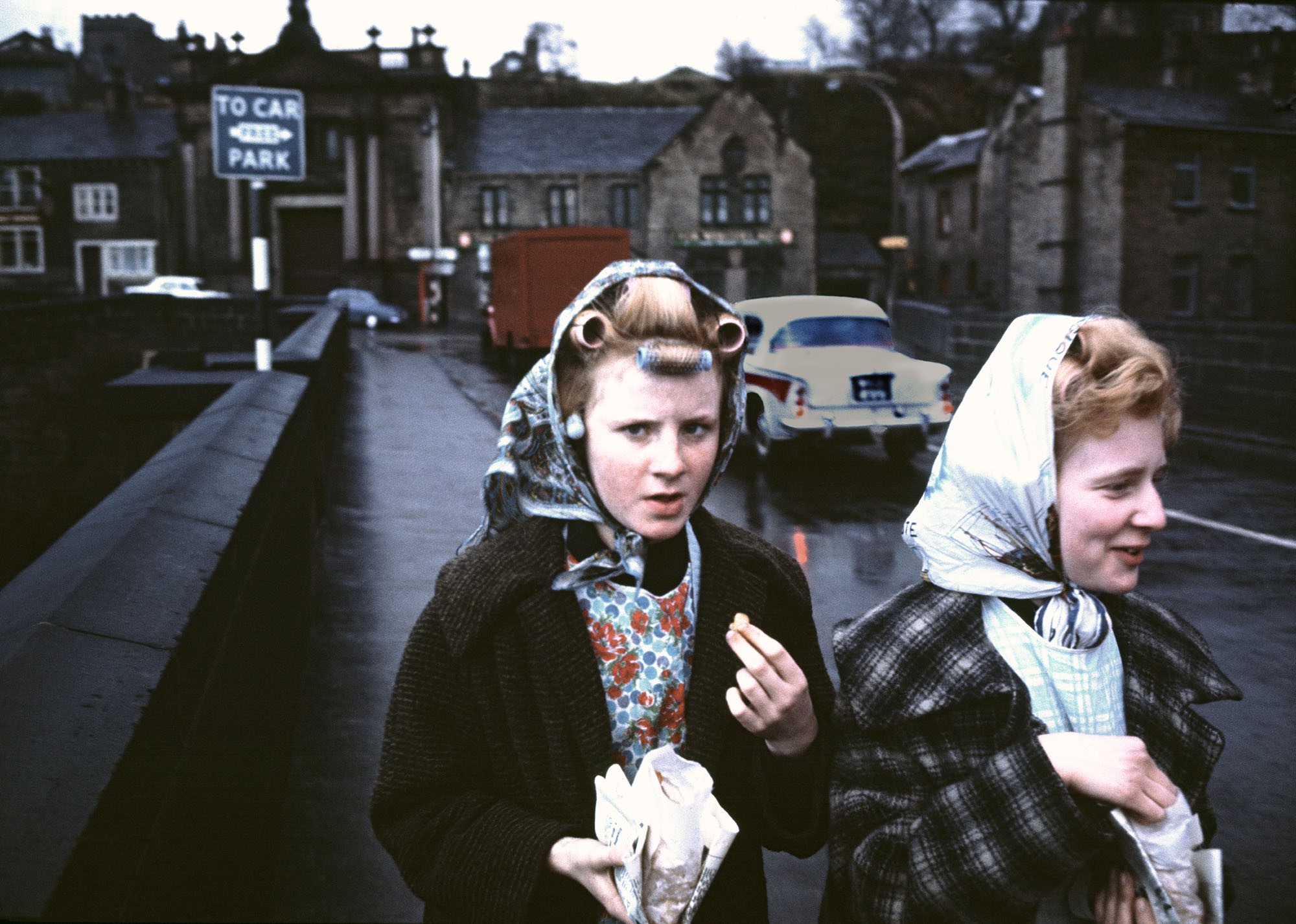 two young girls wearing rollers and hair scarves and eating chips