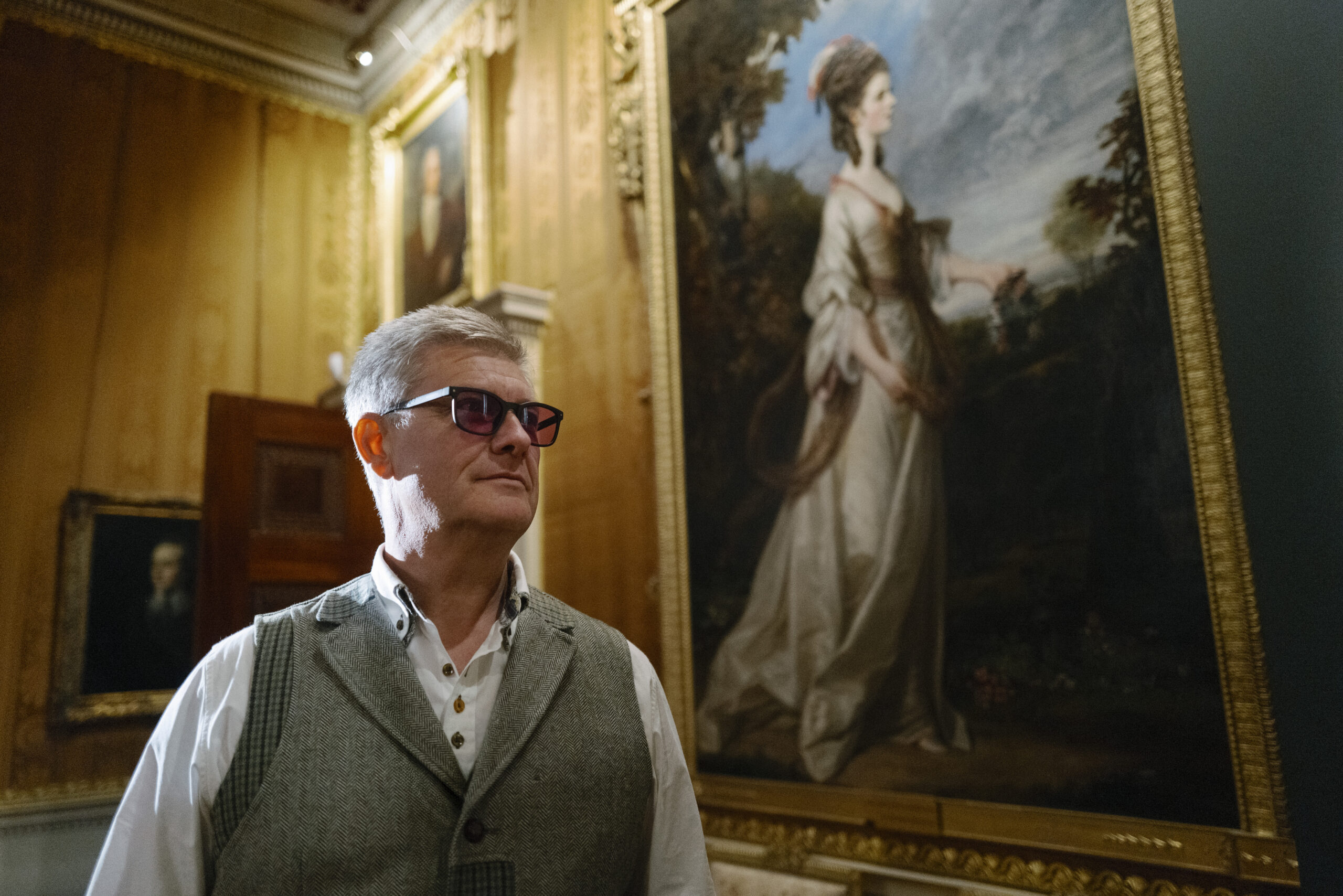 A man wearing enchroma glasses to view a portrait at Harewood House