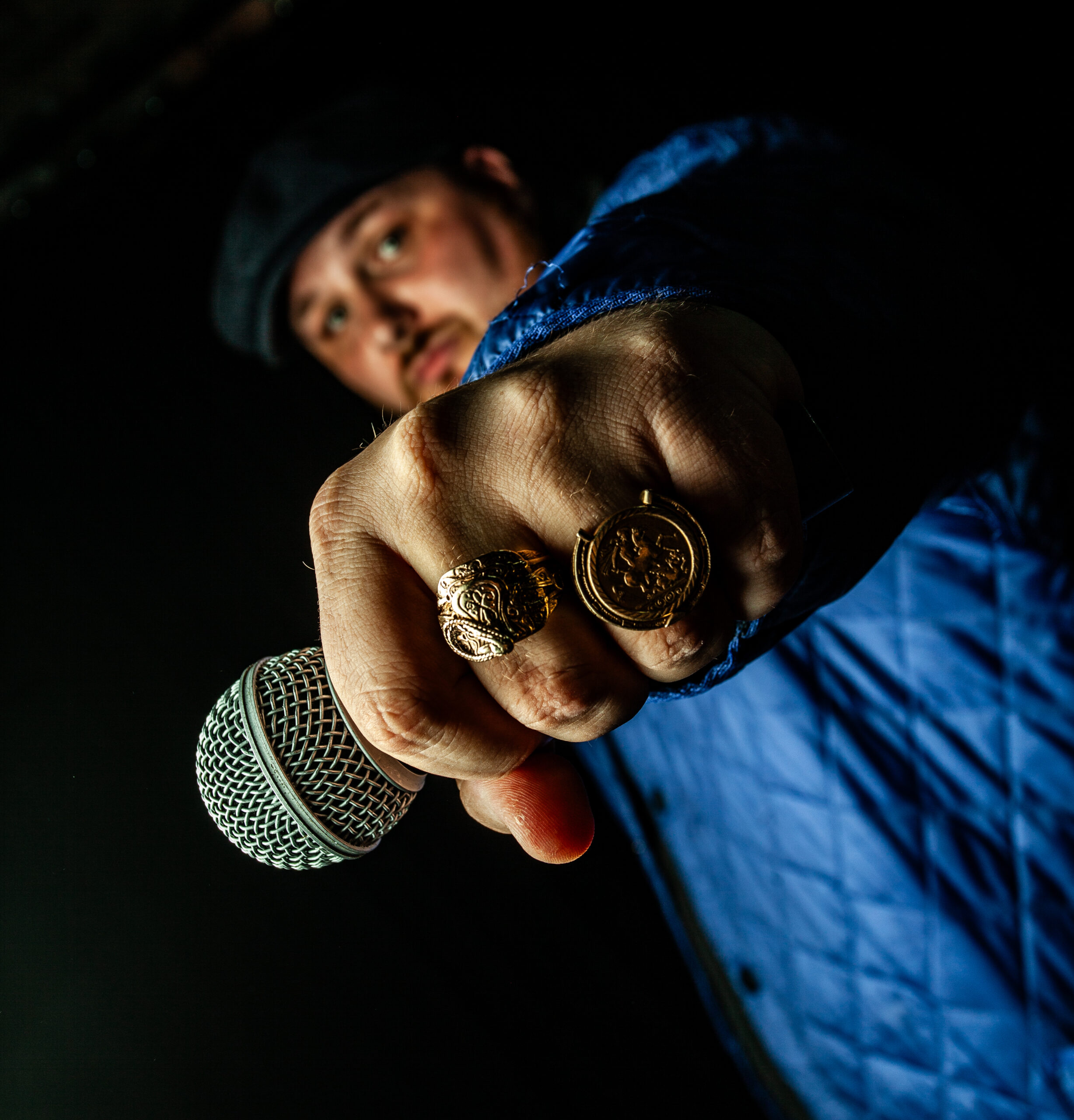 a man holding a microphone and several rings on his hand