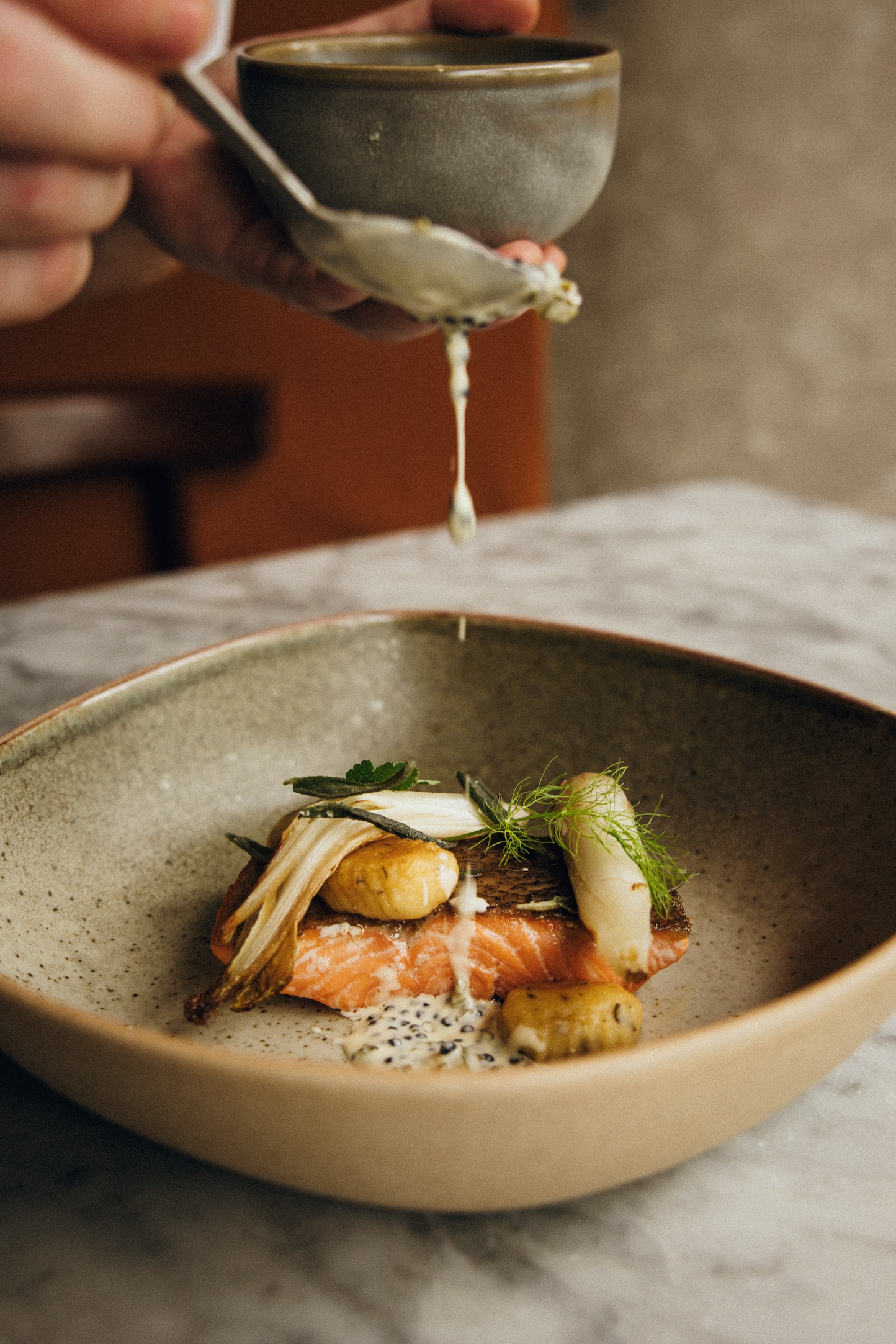 a plate of food with somebody pouring a sauce over