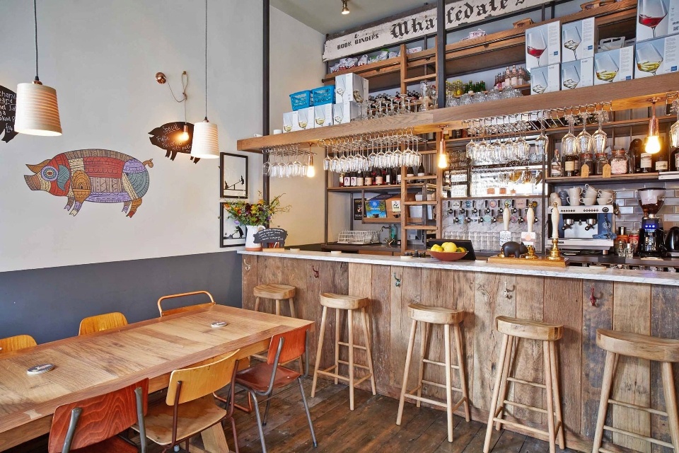 Interior of Friends of Ham cafe bar in Ilkey showing the bar area with stools and banquette seating.