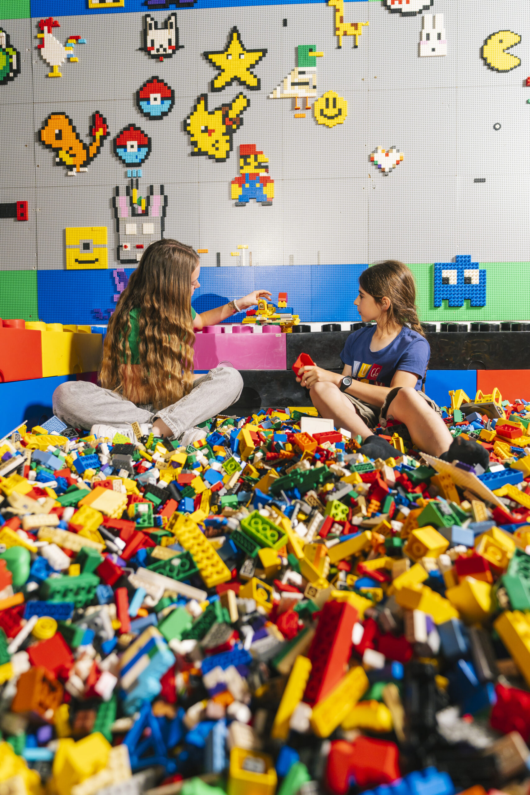 children playing in a pool of colourful lego pieces