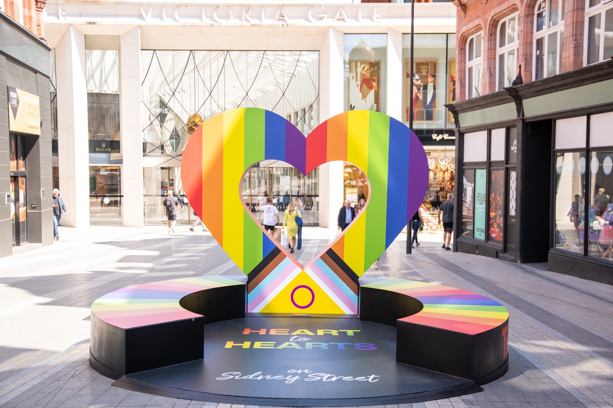a sculpture of a heart with the pride flag and seating around