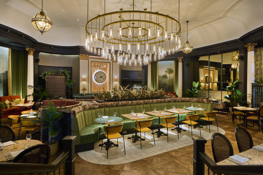 the inside of a restaurant showing booths, tables and chairs under a decorative glass chandelier