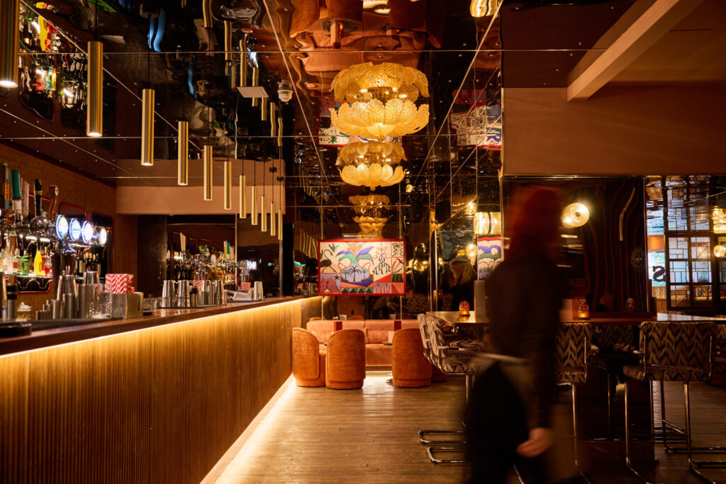 an ornate warmly lit bar with dining tables and chairs