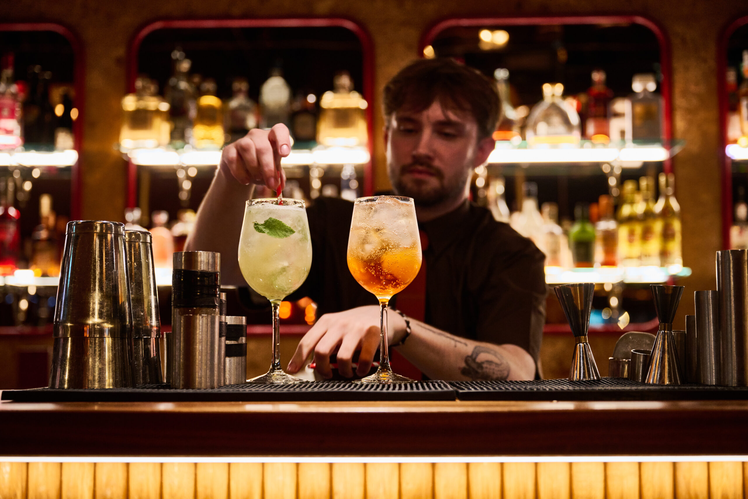 a bartender pouring 2 cocktails