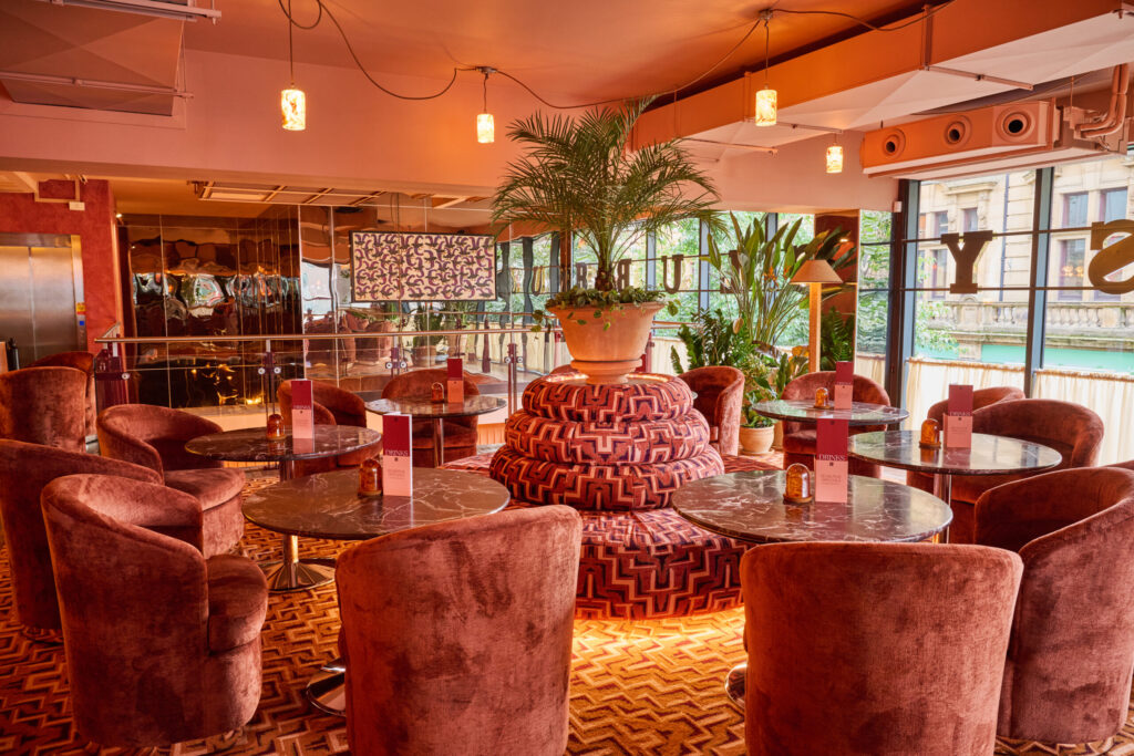 lots of warmly lit round tables and chairs and a round sofa in the middle