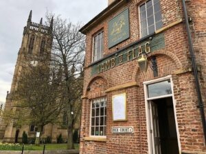 a pub exterior in front of a tree and a church