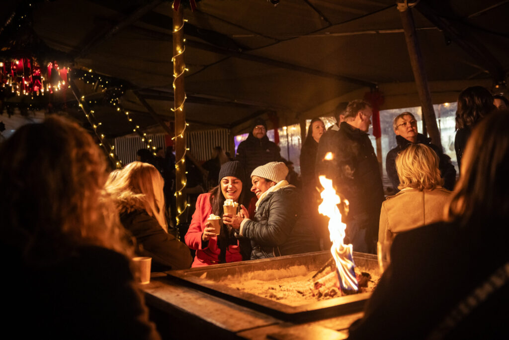 a group of people drinking hot chocolate around a fire in a tipi
