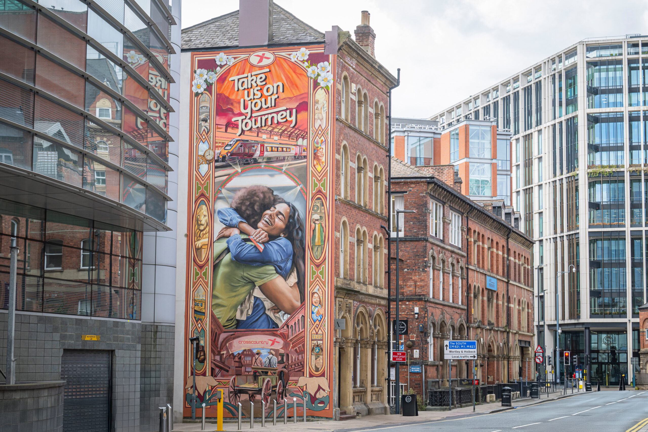 a large mural on the side of a building depicting a crosscountry railway advert of people hugging and leeds landmakrs