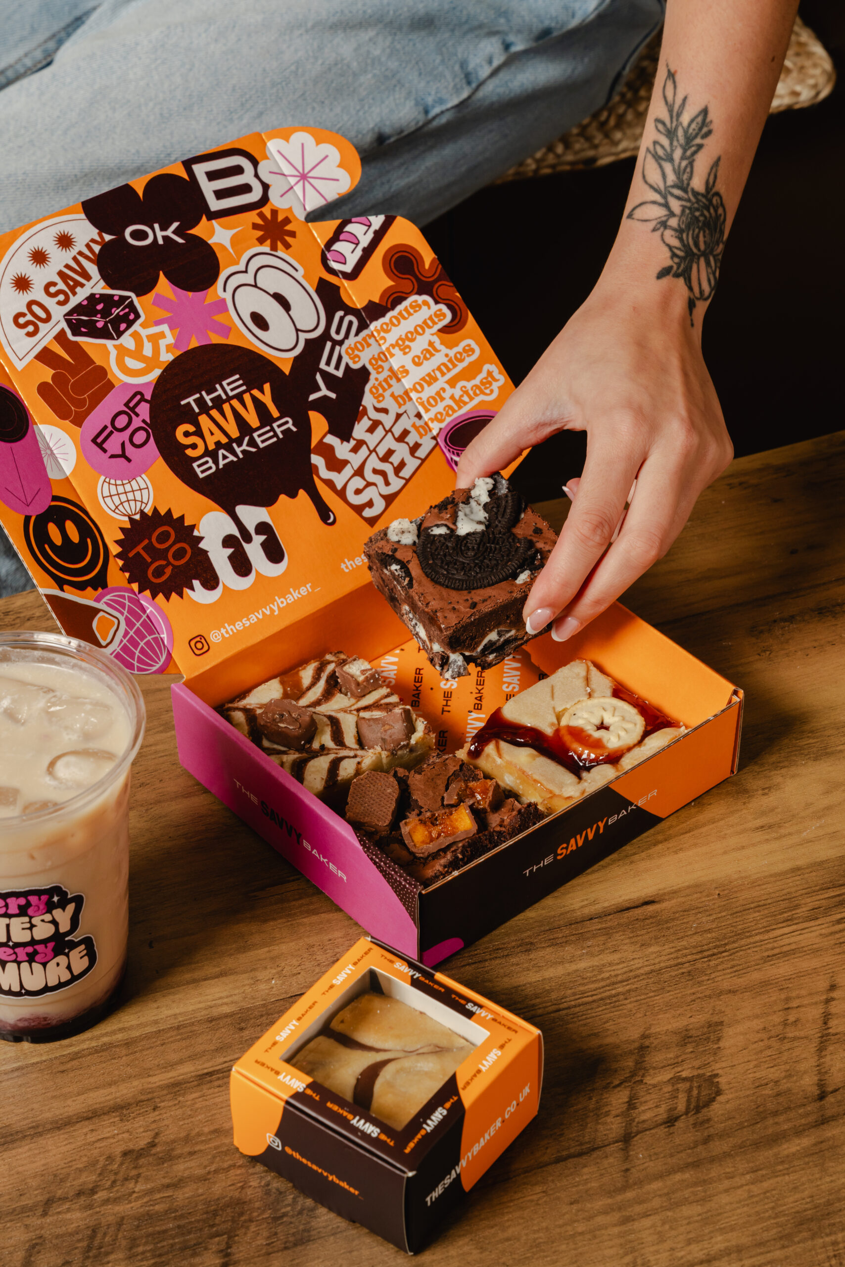 a box with the savvy baker logo on filled with brownies and a coffee