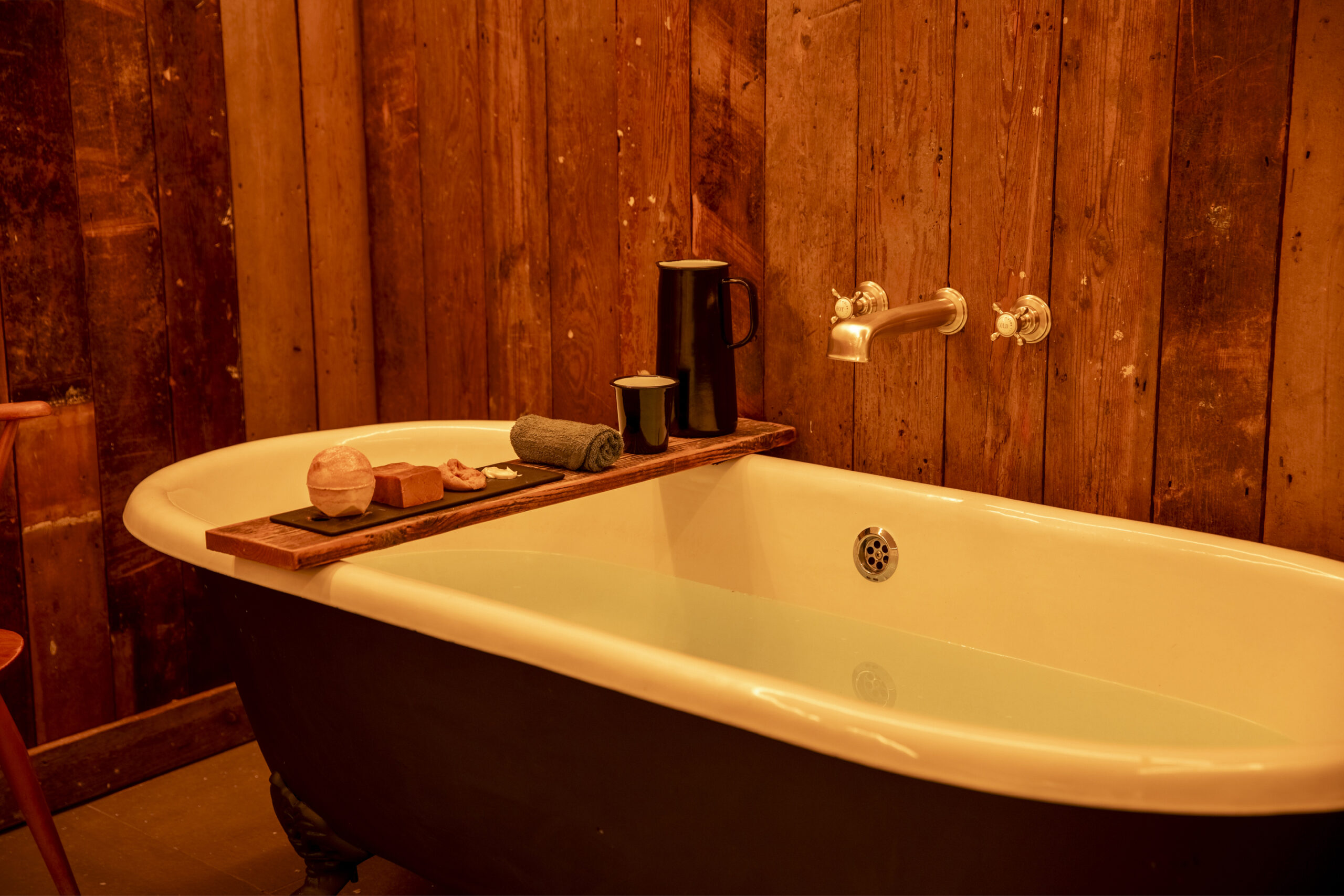 a bath with a wooden shelf featuring lots of products