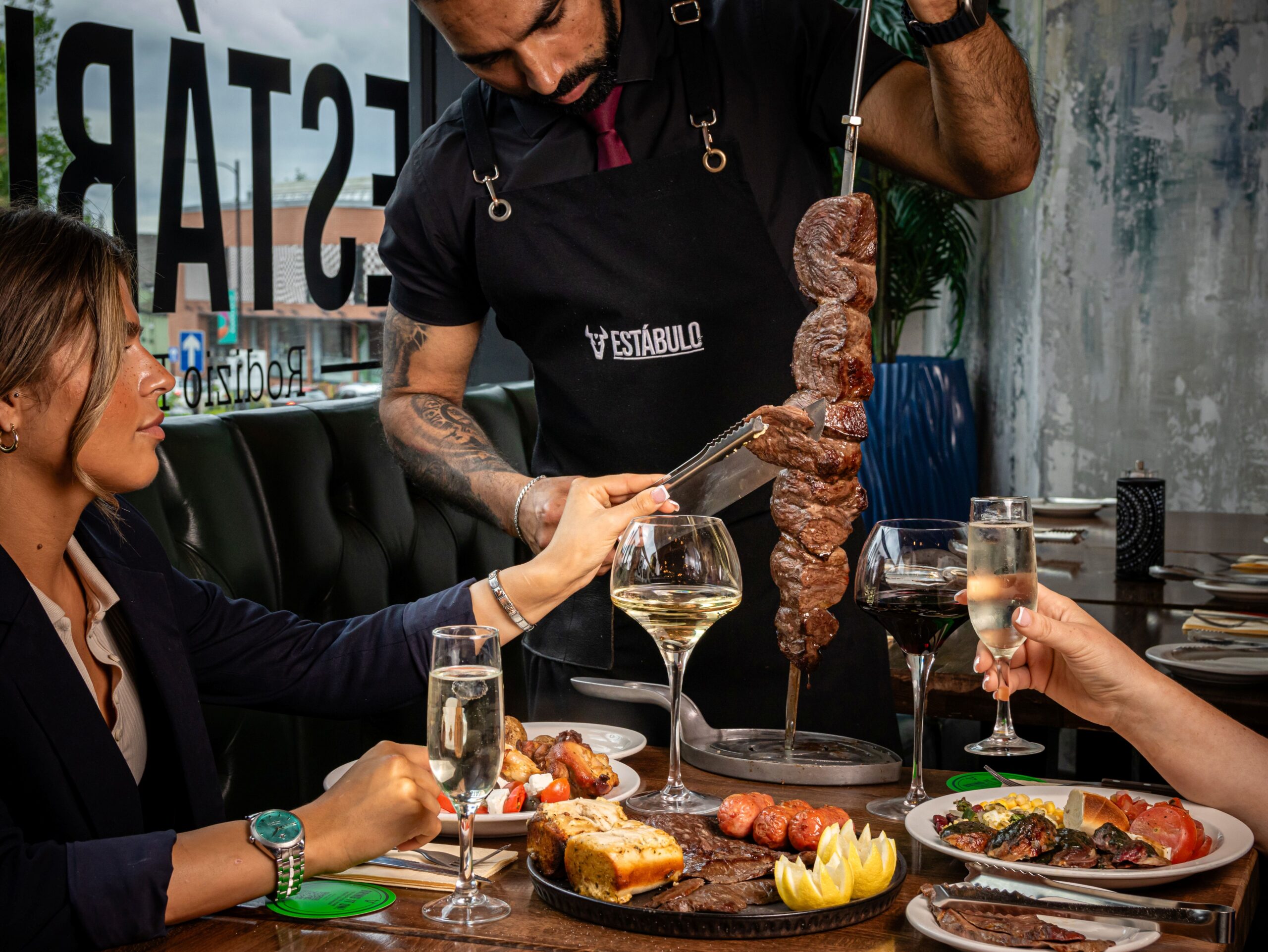 a waiter cutting a kebab of meat at a dinner table