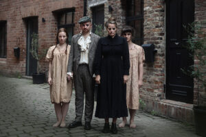 four scare actors in ragged costumes stood in front of a brick building