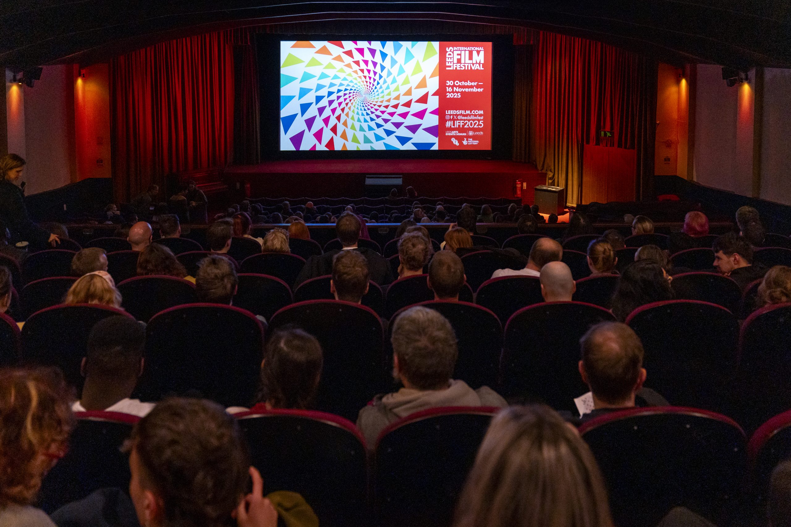 the interior of a cinema screen with people sat watching a a screen