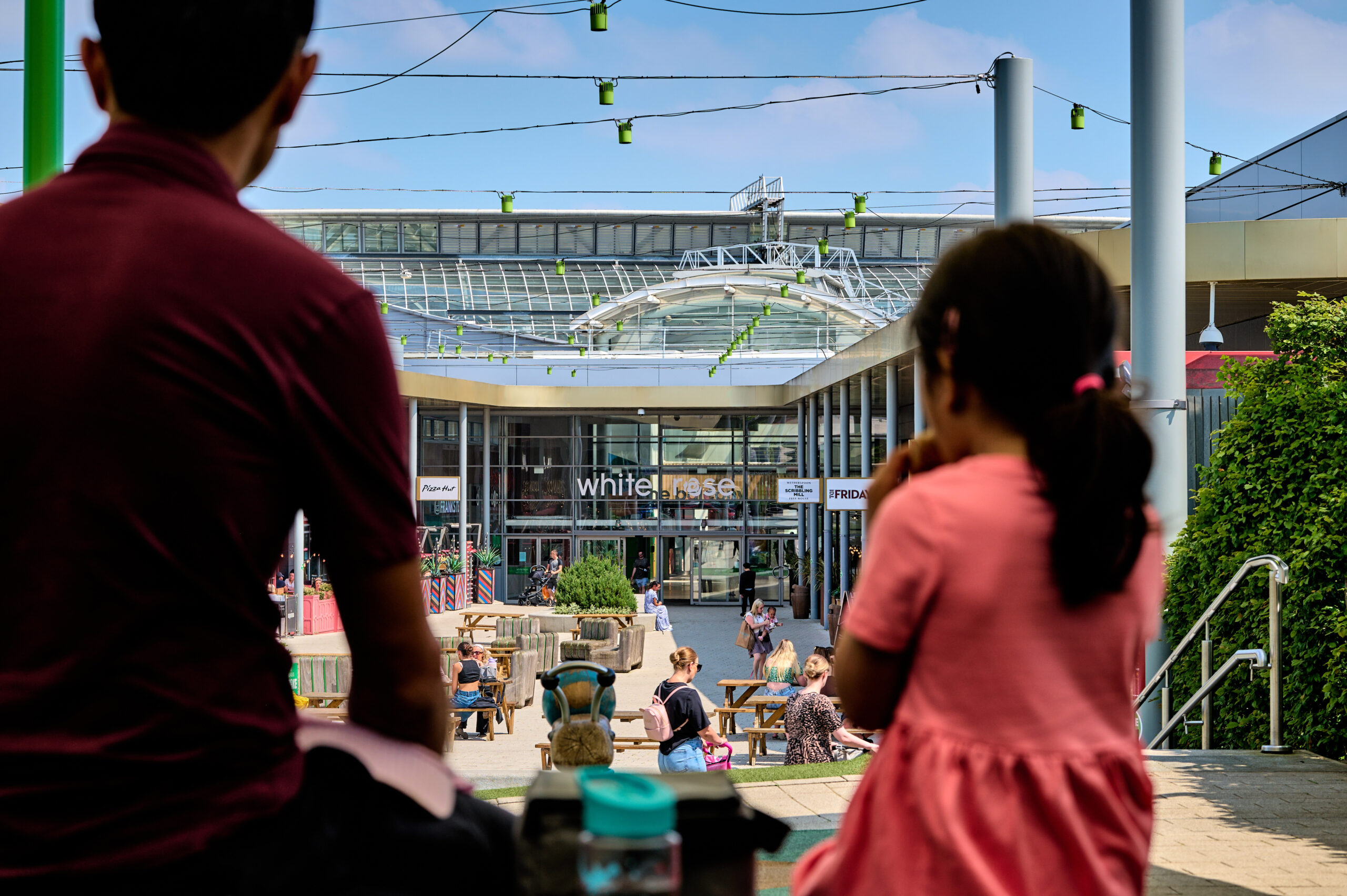 a family sat outside in the sun ina shopping mall picnic area
