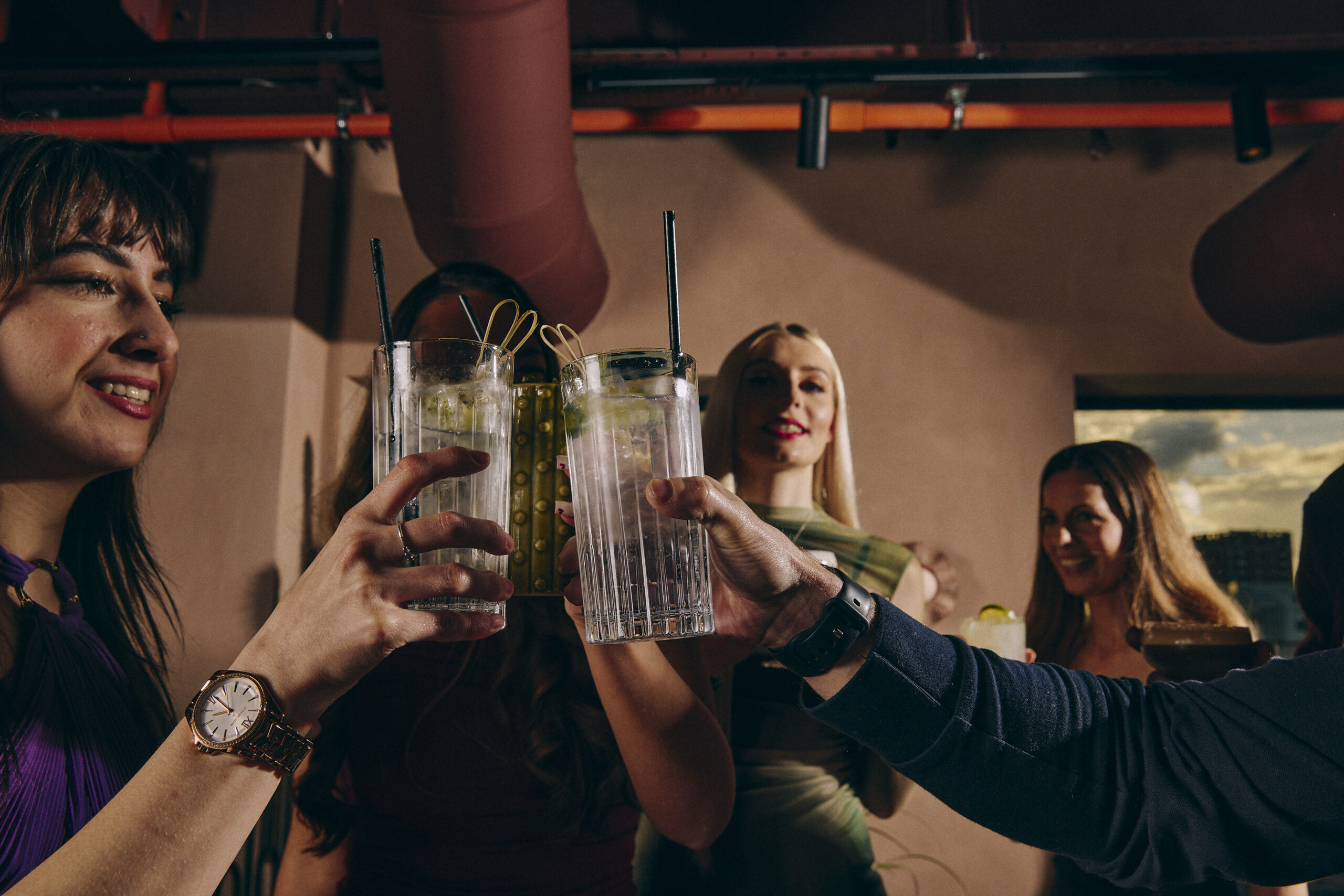 a group of people clinking several large glasses of a drink together
