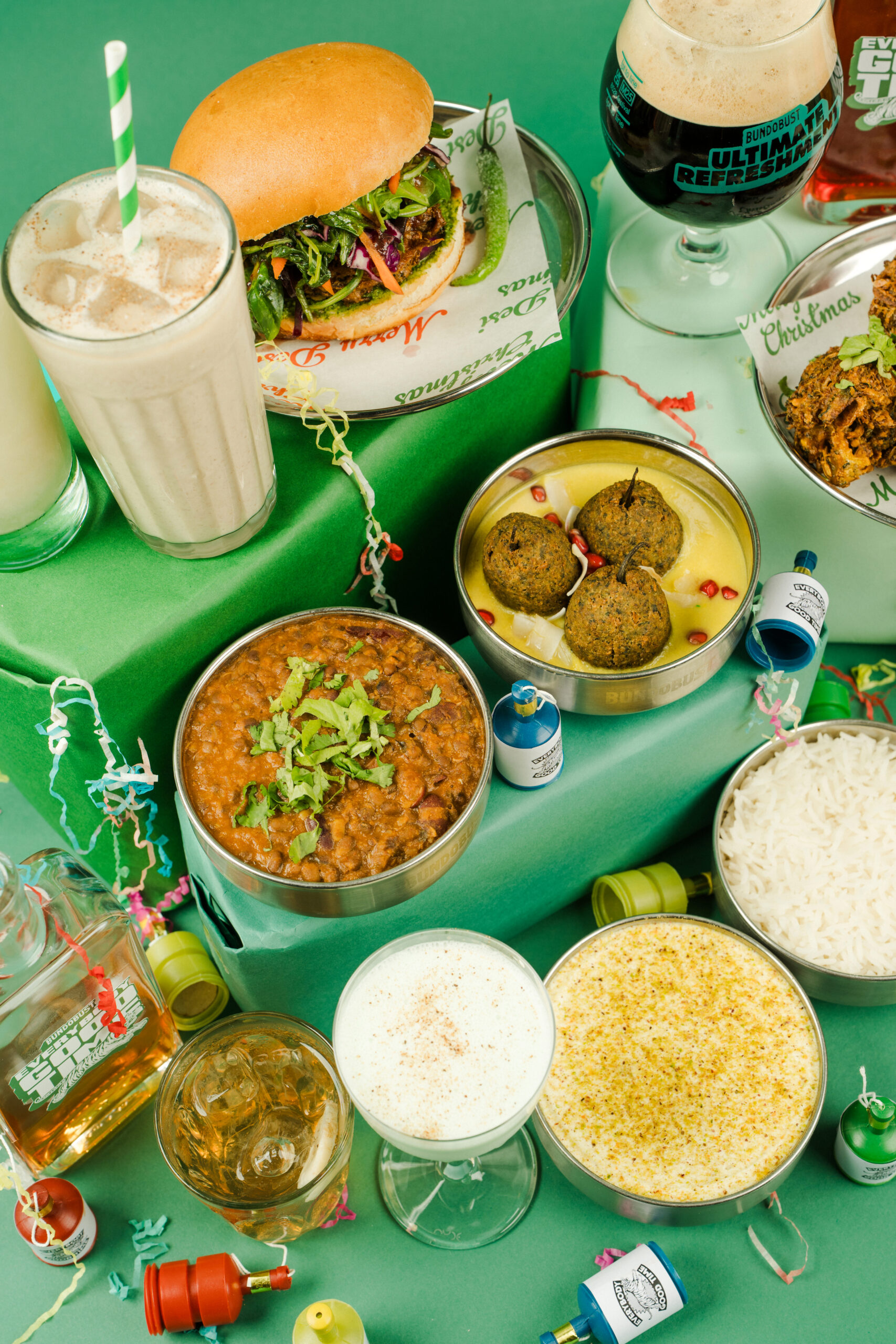 a large display of food and drink on a green background with lots of party poppers in between the plates and bowls