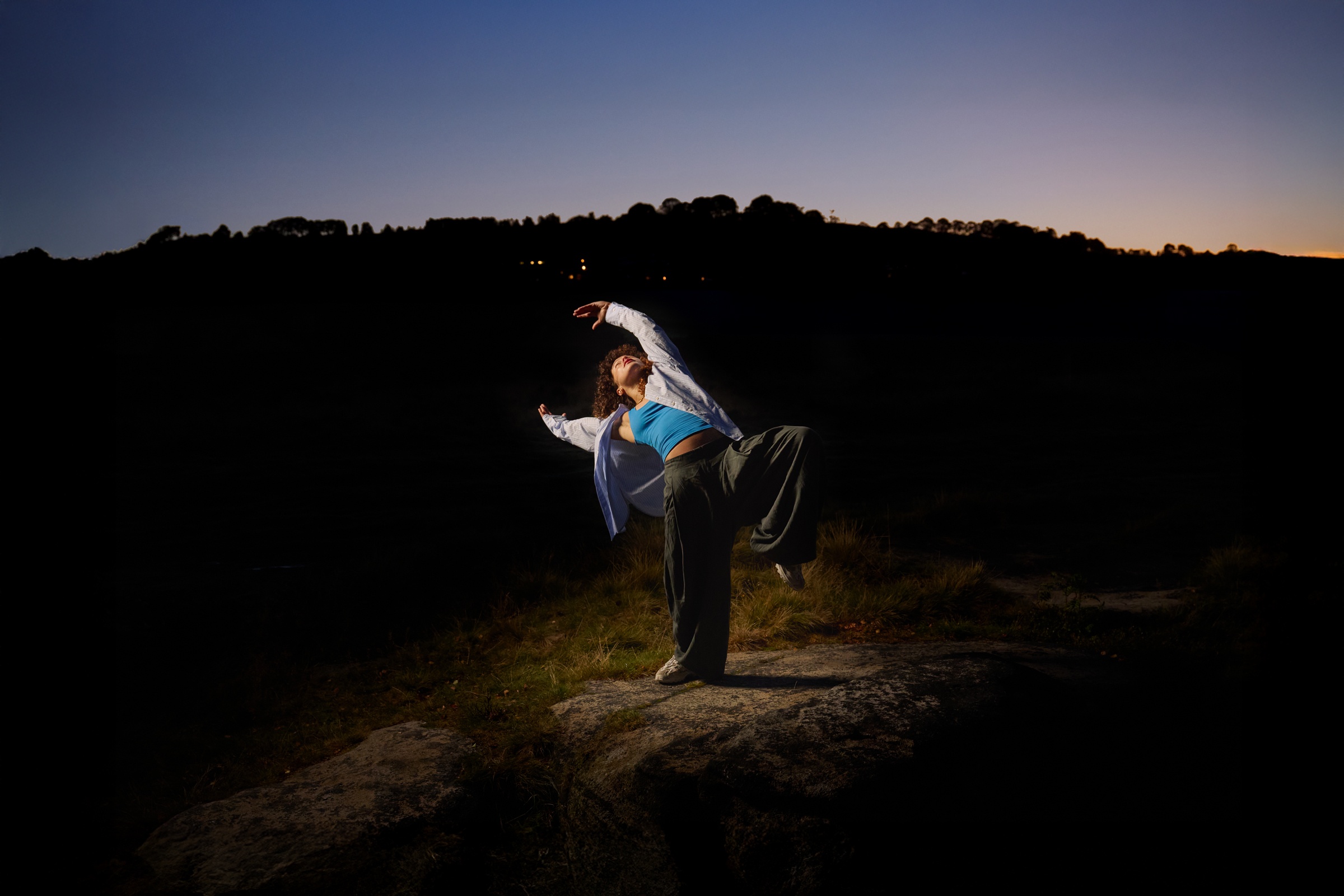 someone dancing outside in the dark with a spotlight on them