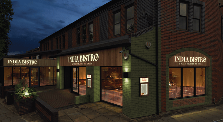 a night time shot of a building with signs saying india bistro