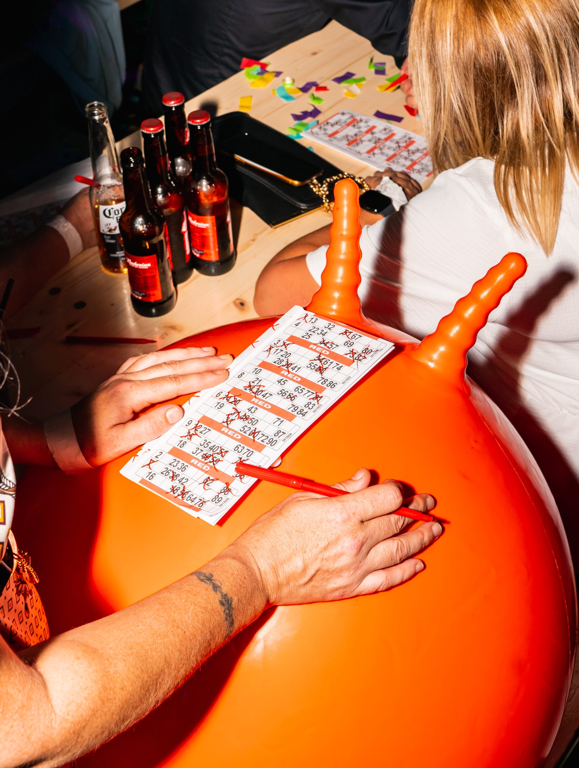 someone writing on a bingo card resting on a bright orange space hopper