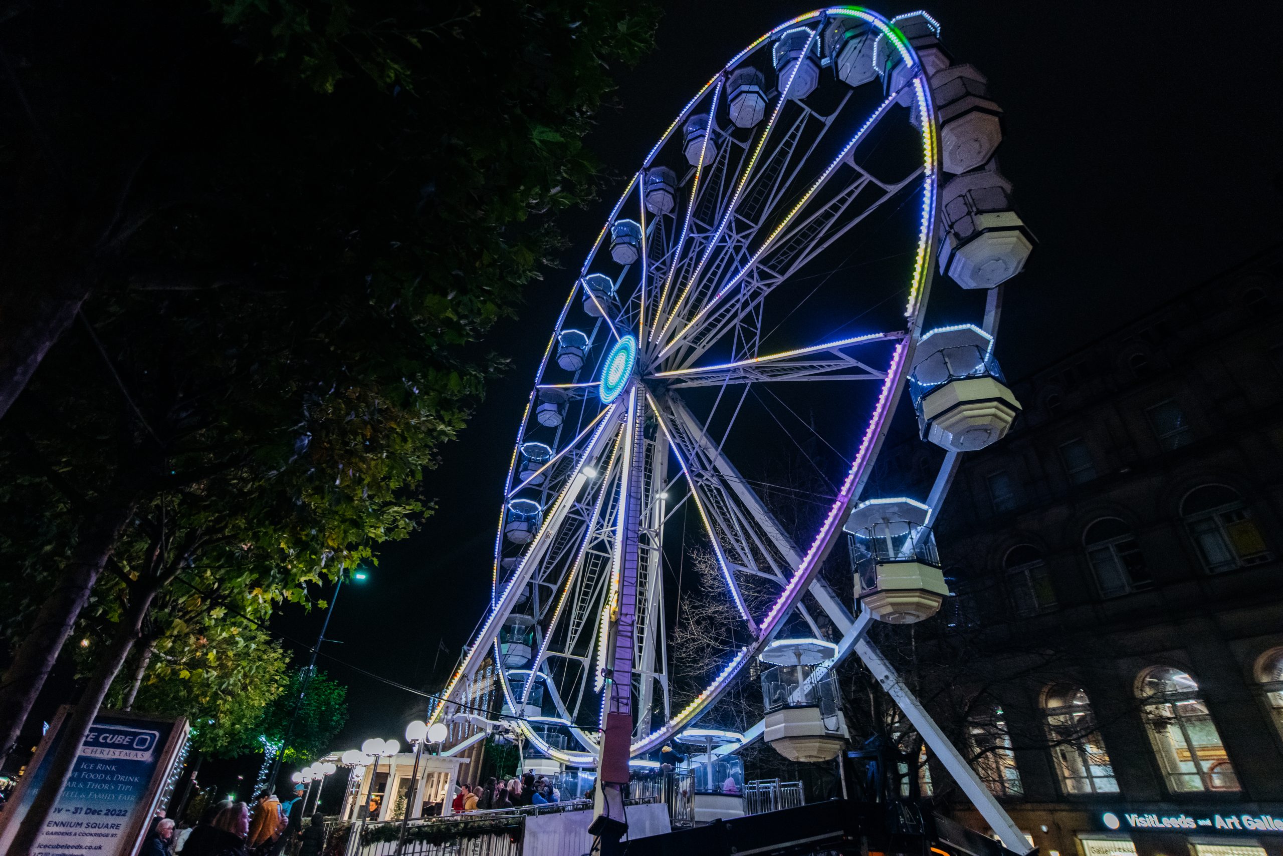 a large ferris wheel with blue and purple lights shining through